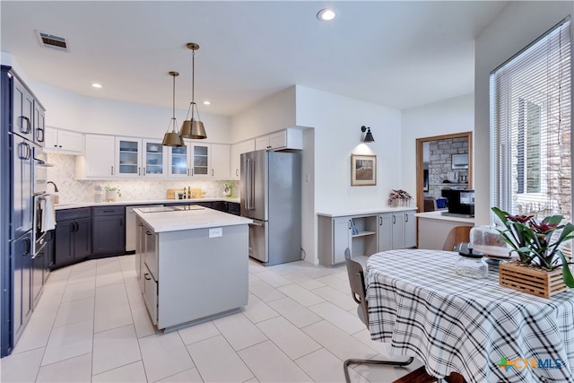 kitchen featuring white cabinets, gray cabinets, a kitchen island, stainless steel refrigerator, and pendant lighting