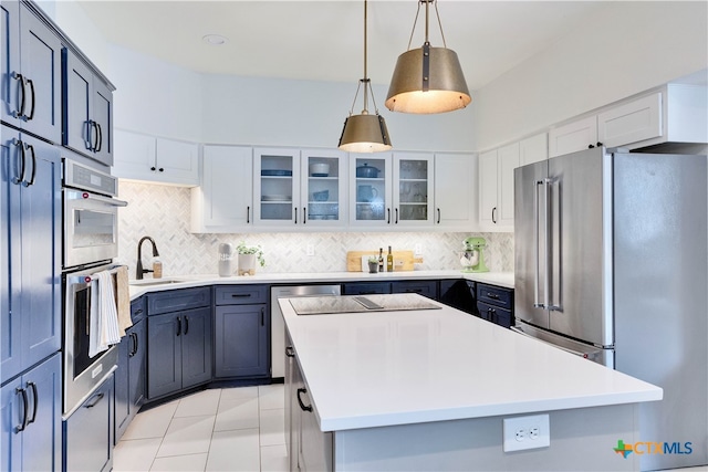 kitchen featuring stainless steel appliances, white cabinets, sink, a kitchen island, and decorative light fixtures