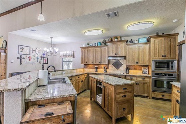127 Hamer Dr, Salado, TX 76571 - kitchen featuring appliances with stainless steel finishes, a sink, under cabinet range hood, tasteful backsplash, and a peninsula