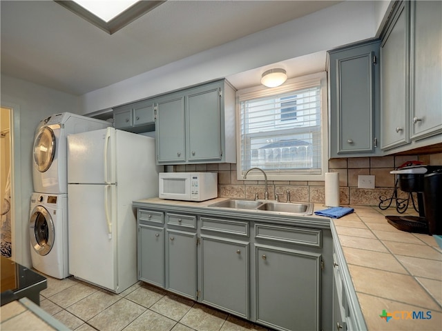 kitchen with stacked washer and dryer, decorative backsplash, sink, and white appliances