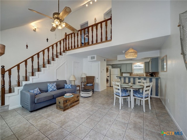 living room with a towering ceiling, ceiling fan, light tile patterned floors, and sink