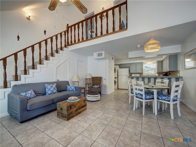 living room with ceiling fan, sink, light tile patterned flooring, and a towering ceiling