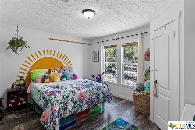 bedroom with dark hardwood / wood-style floors and a textured ceiling