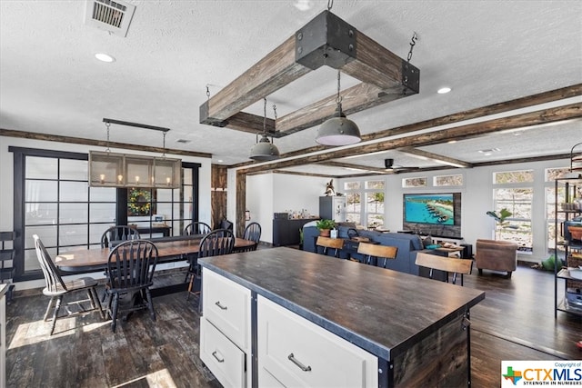 kitchen featuring a kitchen island, a textured ceiling, white cabinetry, and a healthy amount of sunlight