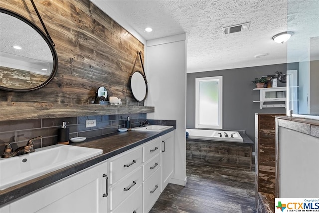 bathroom featuring hardwood / wood-style floors, wood walls, a textured ceiling, vanity, and a bath