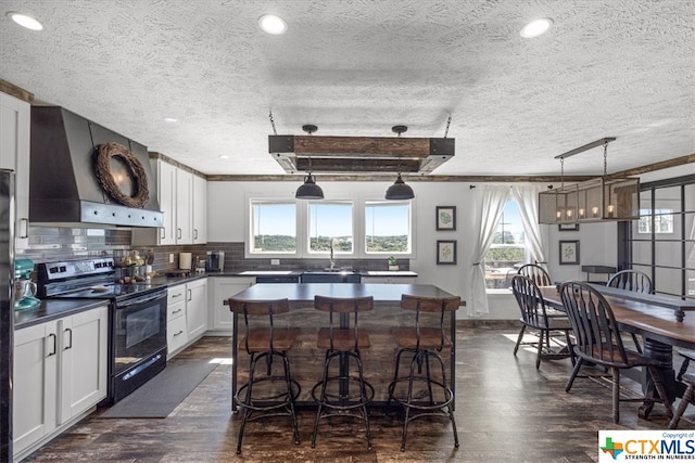 kitchen with pendant lighting, a textured ceiling, black range with electric stovetop, dark hardwood / wood-style floors, and white cabinetry