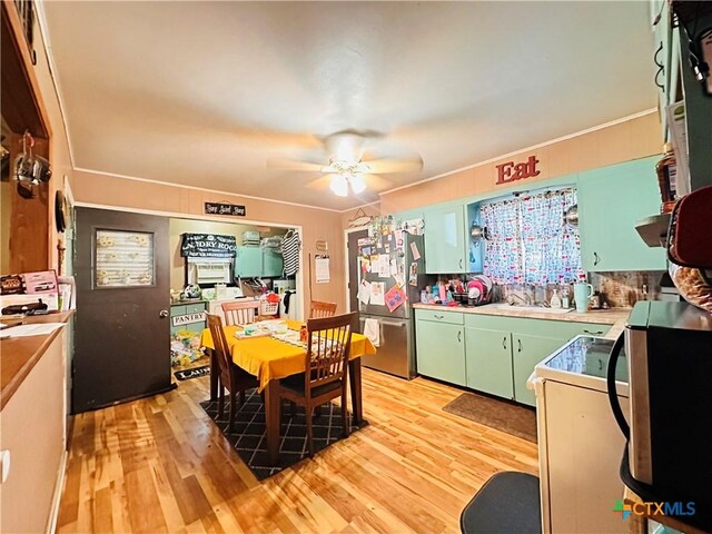 27 County Road 398, TX 77987 - kitchen with light wood finished floors, freestanding refrigerator, green cabinetry, ceiling fan, and light countertops