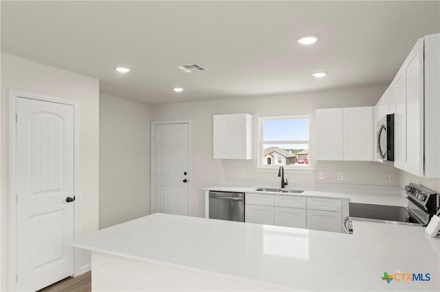 3820 Keller Rd, Temple, TX 76504 - kitchen featuring appliances with stainless steel finishes, a peninsula, recessed lighting, white cabinetry, and light countertops