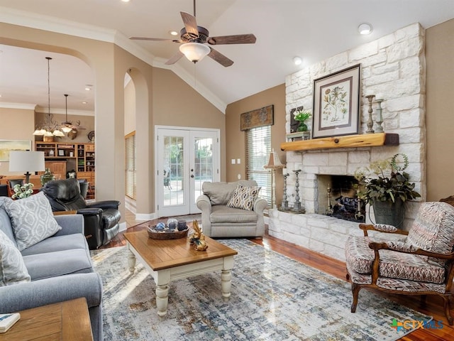 living room featuring crown molding, a stone fireplace, high vaulted ceiling, hardwood / wood-style flooring, and ceiling fan with notable chandelier