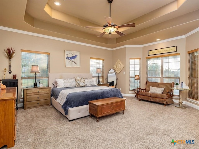 carpeted bedroom with a tray ceiling, ceiling fan, and crown molding