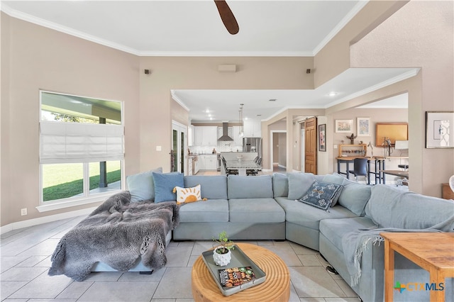 tiled living room with ceiling fan and ornamental molding