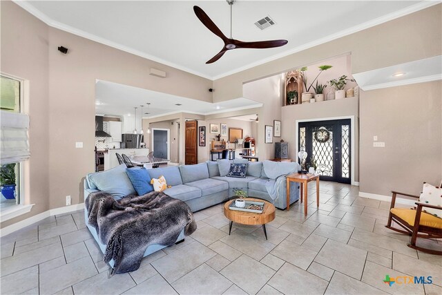 living room featuring ceiling fan, ornamental molding, and a towering ceiling