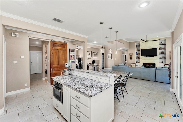 kitchen featuring stainless steel oven, a breakfast bar, a kitchen island, pendant lighting, and white cabinetry