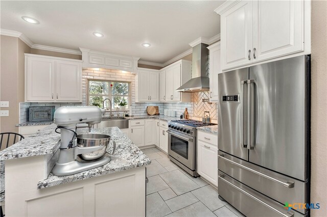 kitchen featuring light stone countertops, tasteful backsplash, wall chimney exhaust hood, premium appliances, and white cabinets