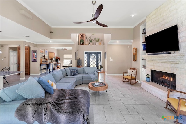 living room with ceiling fan, ornamental molding, a fireplace, and light tile patterned floors