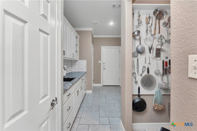 bathroom featuring a workshop area, ornamental molding, and backsplash