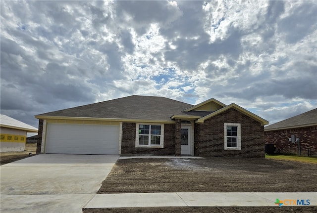 ranch-style home with a garage and central air condition unit