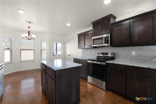 kitchen with decorative backsplash, appliances with stainless steel finishes, decorative light fixtures, light stone counters, and a chandelier