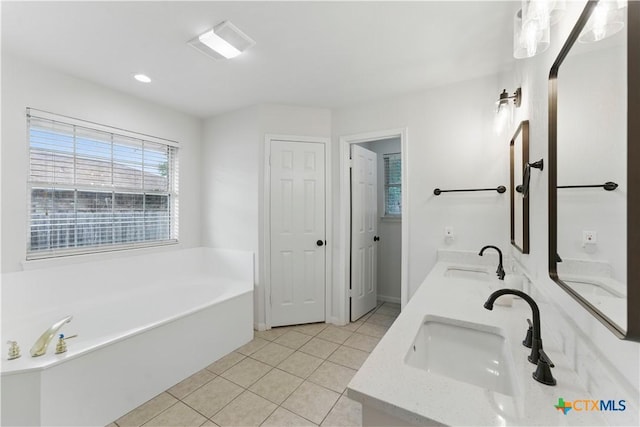 full bath featuring a bath, tile patterned floors, a sink, and double vanity