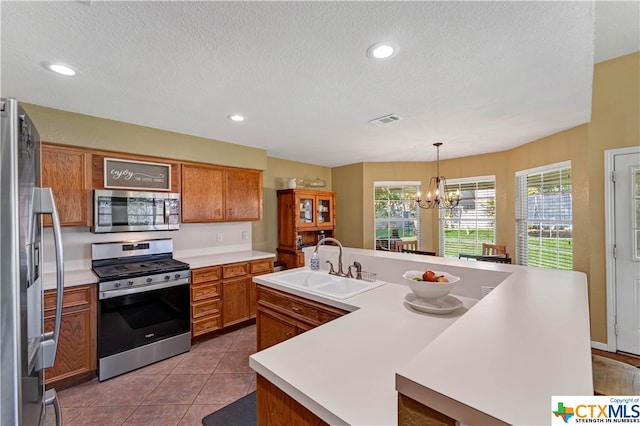 kitchen with a kitchen island with sink, sink, hanging light fixtures, appliances with stainless steel finishes, and a notable chandelier