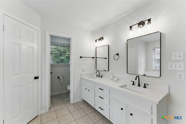 bathroom featuring tile patterned flooring, toilet, baseboards, and a sink