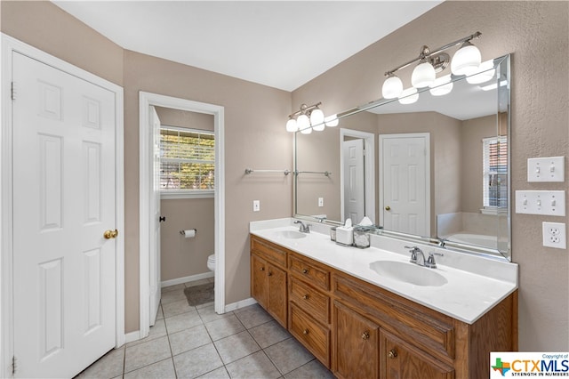 bathroom with tile patterned floors, a washtub, vanity, and toilet