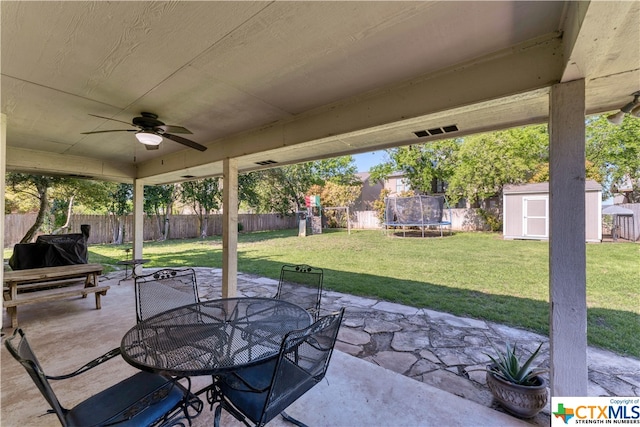 view of patio with ceiling fan, a shed, and a trampoline