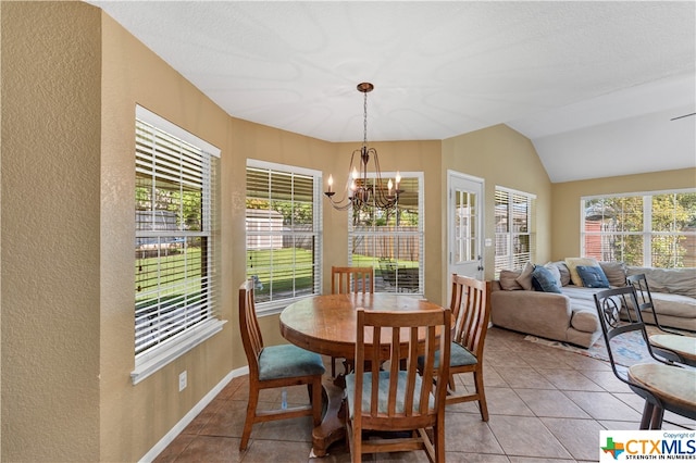 tiled dining space featuring lofted ceiling, a healthy amount of sunlight, and a notable chandelier