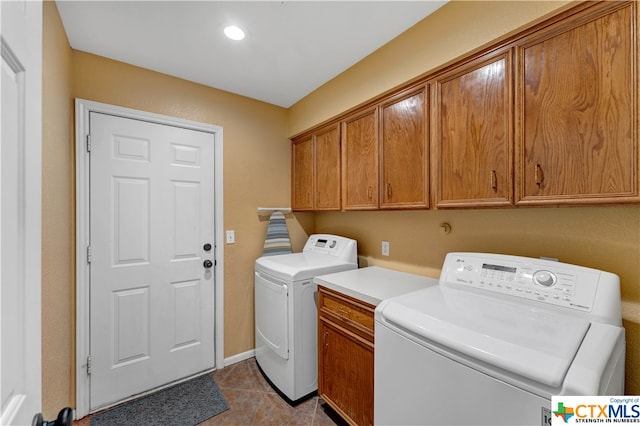 laundry area featuring cabinets, light tile patterned floors, and washer and clothes dryer