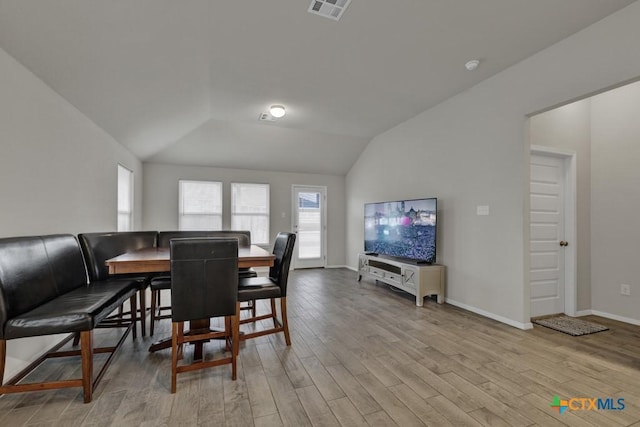 dining room with lofted ceiling, light wood finished floors, visible vents, and baseboards