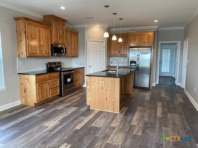 kitchen with stainless steel appliances, dark hardwood / wood-style flooring, sink, a kitchen island with sink, and pendant lighting