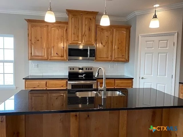 kitchen with appliances with stainless steel finishes, sink, and decorative light fixtures