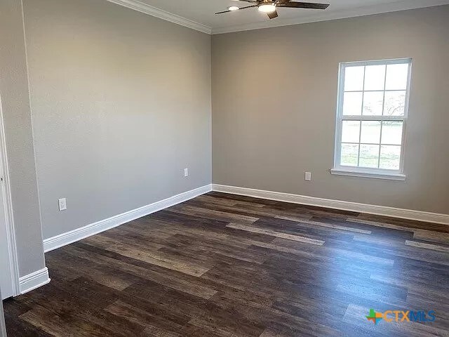 unfurnished room featuring ceiling fan, dark hardwood / wood-style floors, and crown molding