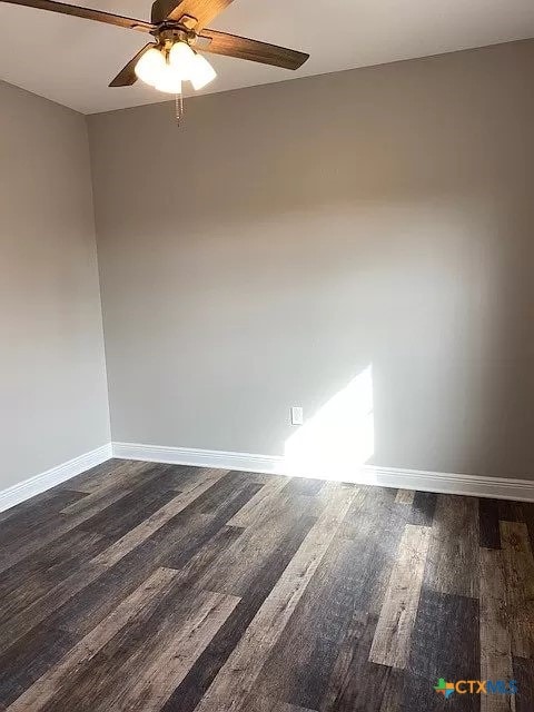 empty room featuring dark wood-type flooring and ceiling fan