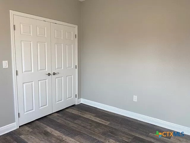 unfurnished bedroom with a closet and dark hardwood / wood-style flooring