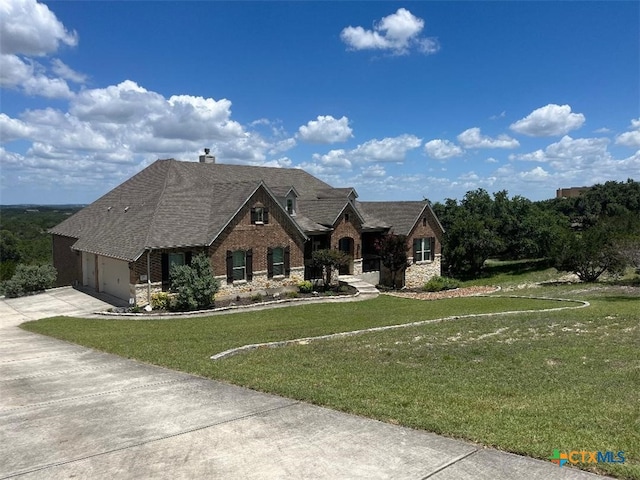 view of front of house with a garage, brick siding, driveway, a front lawn, and a chimney