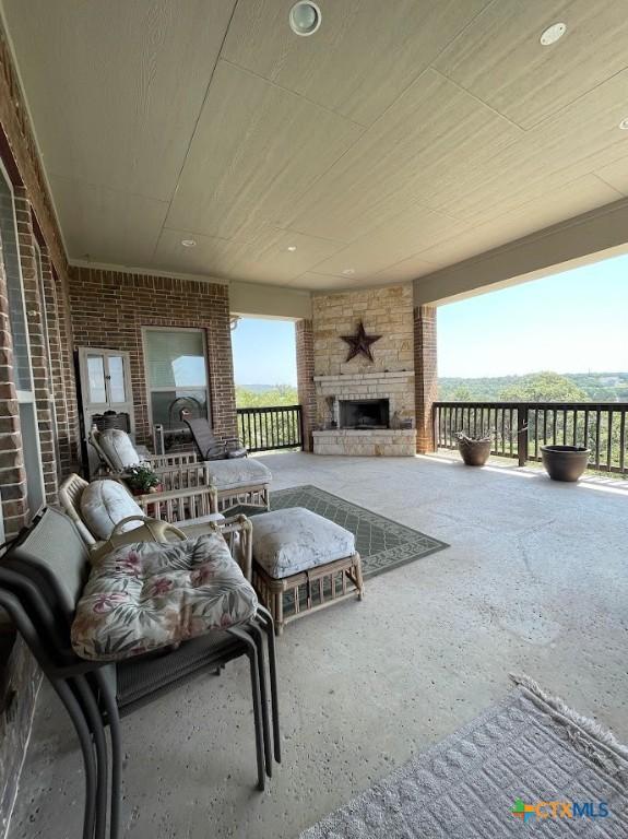 unfurnished living room with an outdoor stone fireplace and brick wall