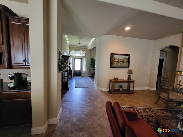 entrance foyer featuring arched walkways, tile patterned flooring, crown molding, and baseboards