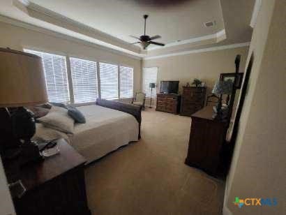 bedroom featuring ornamental molding, a tray ceiling, carpet flooring, and a ceiling fan