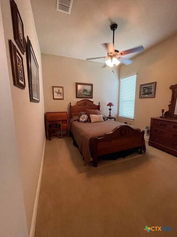 bedroom with baseboards, visible vents, a ceiling fan, and light colored carpet