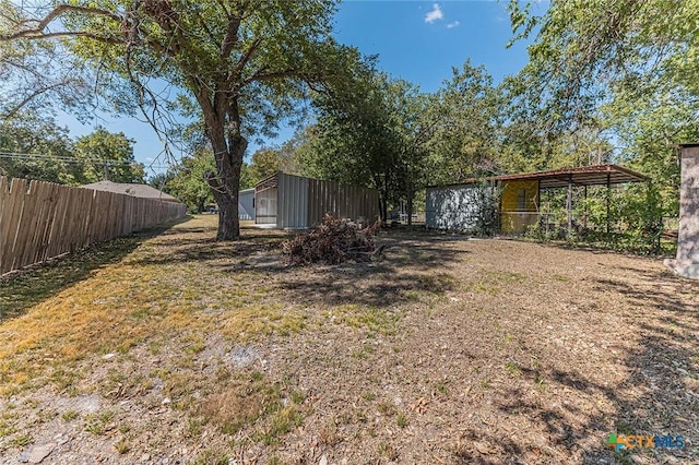 view of yard featuring a pole building, fence, and an outdoor structure