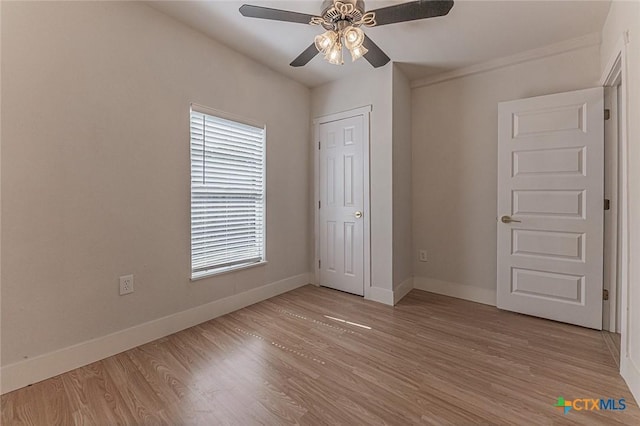 spare room featuring light wood-type flooring, a ceiling fan, and baseboards