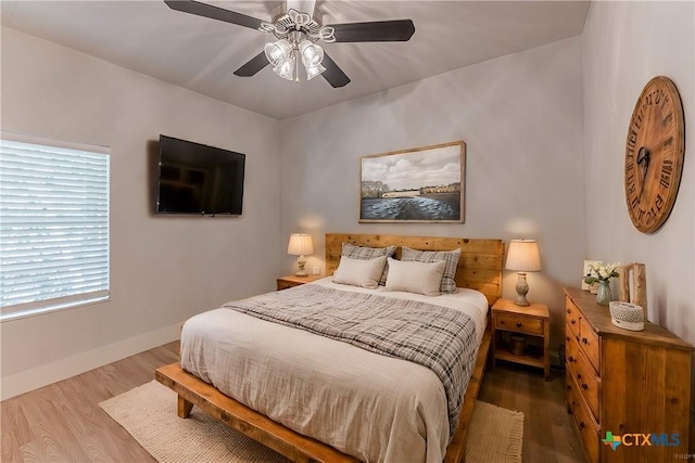 bedroom featuring wood finished floors, a ceiling fan, and baseboards