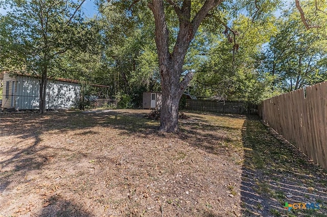 view of yard featuring a storage shed, a fenced backyard, and an outbuilding