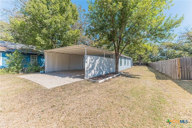 garage featuring a detached carport, fence, and driveway