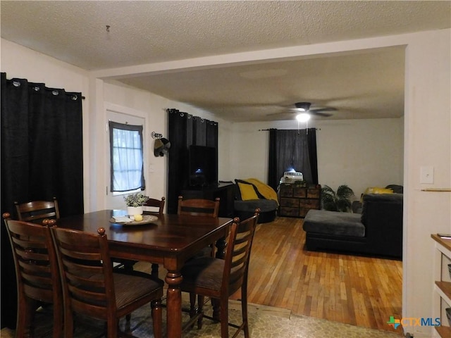 dining room with ceiling fan, a textured ceiling, and light wood-type flooring