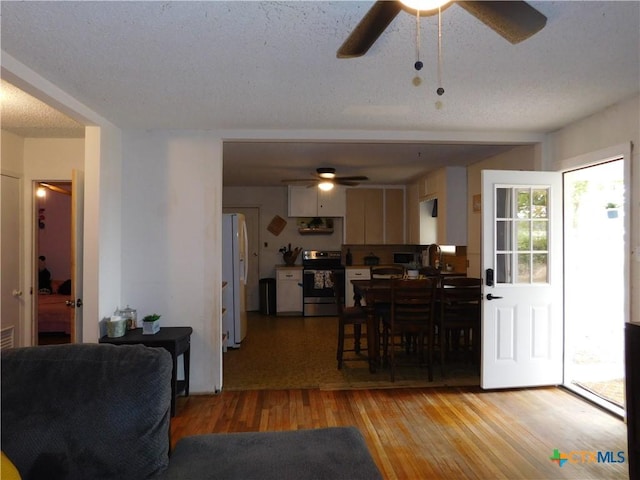 dining space featuring ceiling fan, sink, a textured ceiling, and light wood-type flooring