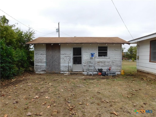 rear view of property with a lawn and an outdoor structure