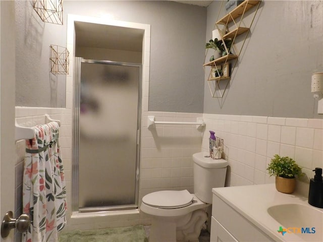 bathroom with vanity, toilet, a shower with door, and tile walls