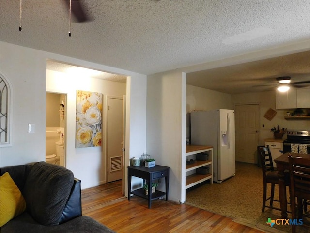 living room featuring ceiling fan, hardwood / wood-style floors, and a textured ceiling